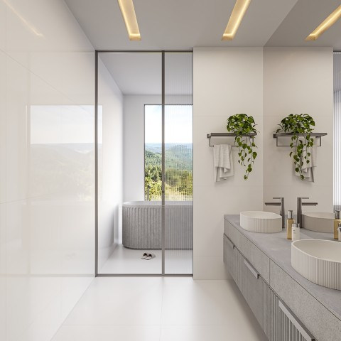 Banheiro de luxo moderno com piso e paredes revestidos de porcelanatos grandes formatos brancos. À direita, uma bancada cinza com cubas de apoio e espelho; ao fundo, uma divisória de vidro canelado revela uma banheira em frente a uma janela com vista para a natureza. Banheiro de luxo moderno com piso e paredes revestidos de porcelanatos grandes formatos brancos. À direita, uma bancada cinza com cubas de apoio e espelho; ao fundo, uma divisória de vidro canelado revela uma banheira em frente a uma janela com vista para a natureza.