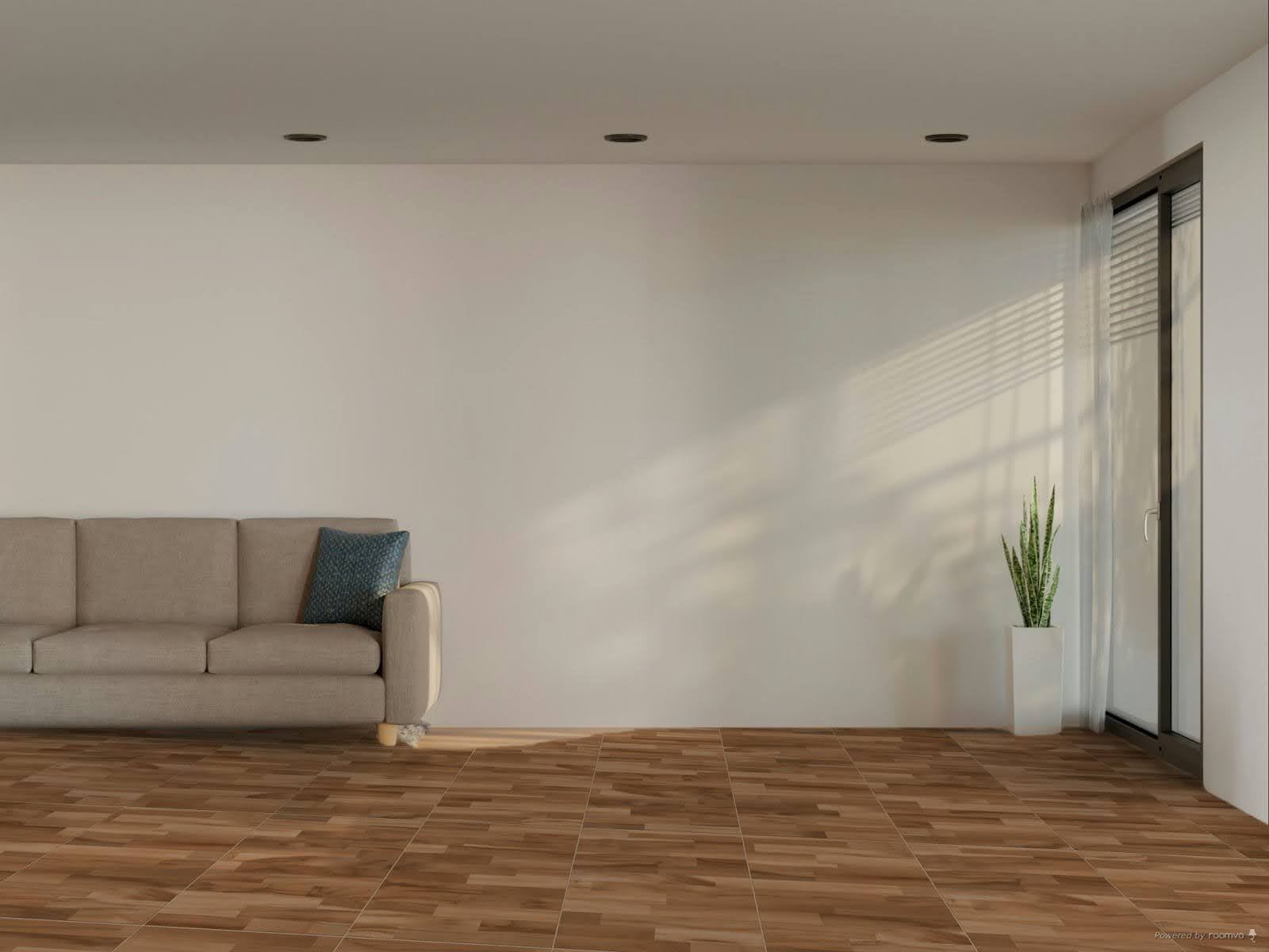 Revestimento amadeirado aplicado no chão de sala ampla com parede branca e sofá cinza encostado na parede.