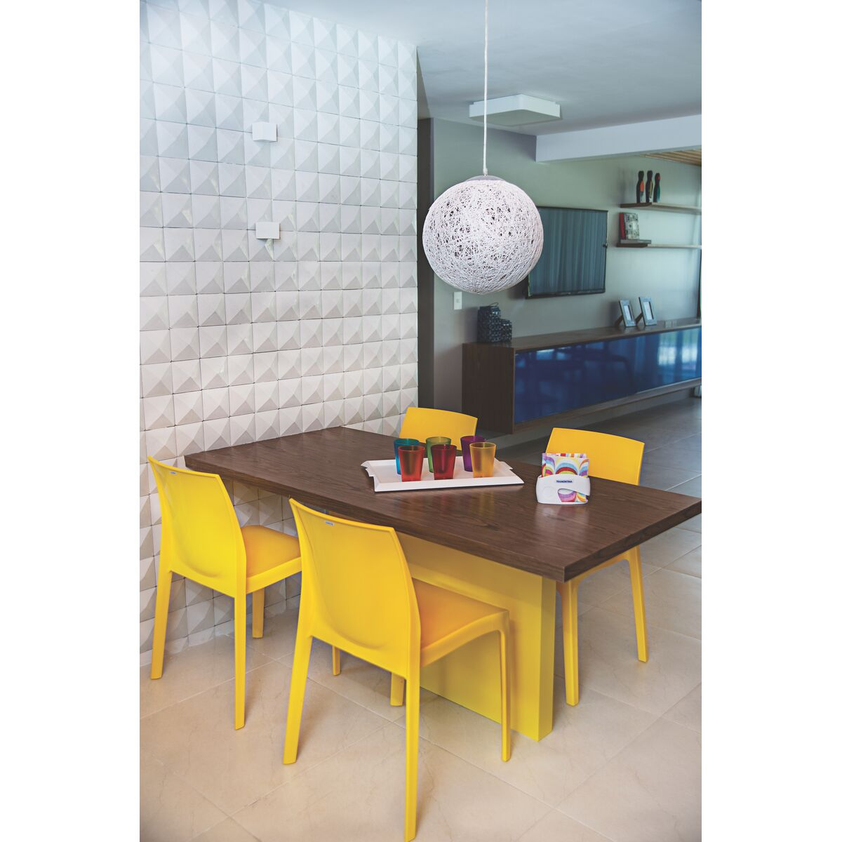 Sala de jantar moderna com mesa retangular de madeira escura e quatro cadeiras de plástico amarelas com design ergonômico e estiloso. Sala de jantar moderna com mesa retangular de madeira escura e quatro cadeiras de plástico amarelas com design ergonômico e estiloso.