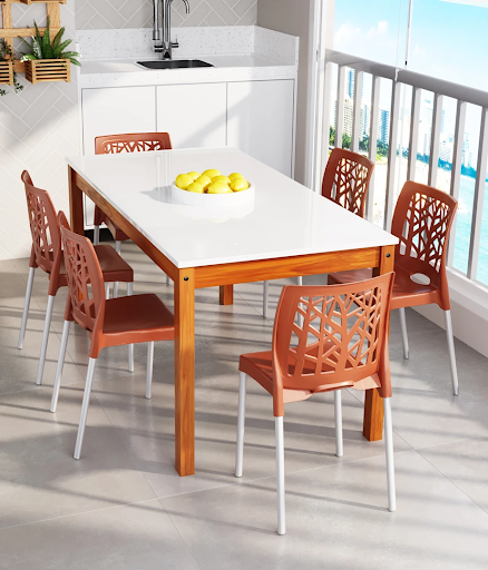 Cozinha moderna integrada à varanda com mesa retangular de madeira e tampo branco, cercada por seis cadeiras de plástico na cor terracota. Cozinha moderna integrada à varanda com mesa retangular de madeira e tampo branco, cercada por seis cadeiras de plástico na cor terracota.
