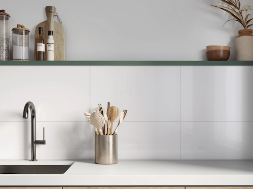 Close em uma cozinha de estilo escandinavo, com foco na área da bancada branca fosca e da cuba embutida. A parede é revestida com peças de cerâmica retangulares brancas de acabamento brilhante, que criam um backsplash clean. Sobre a bancada, um pote metálico dourado segura utensílios de cozinha de madeira e silicone. Acima do backsplash, há uma prateleira verde musgo com potes de mantimentos, azeite, uma tábua de corte de madeira, vasos de cerâmica rústica e ramos secos. Close em uma cozinha de estilo escandinavo, com foco na área da bancada branca fosca e da cuba embutida. A parede é revestida com peças de cerâmica retangulares brancas de acabamento brilhante, que criam um backsplash clean. Sobre a bancada, um pote metálico dourado segura utensílios de cozinha de madeira e silicone. Acima do backsplash, há uma prateleira verde musgo com potes de mantimentos, azeite, uma tábua de corte de madeira, vasos de cerâmica rústica e ramos secos.