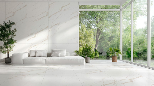 Sala de estar minimalista e ampla revestida com grandes placas de porcelanato marmorizado branco e veios dourados no piso e na parede principal. Um sofá modular branco sem encosto alto está posicionado ao centro, acompanhado por plantas em vasos e uma grande janela de vidro do chão ao teto com vista para árvores e vegetação externa. Sala de estar minimalista e ampla revestida com grandes placas de porcelanato marmorizado branco e veios dourados no piso e na parede principal. Um sofá modular branco sem encosto alto está posicionado ao centro, acompanhado por plantas em vasos e uma grande janela de vidro do chão ao teto com vista para árvores e vegetação externa.