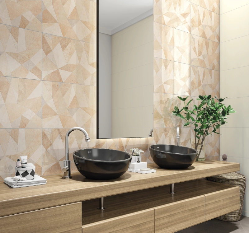 um banheiro moderno com uma parede revestida com cerâmica de estampa geométrica em tons de bege e marrom, com um efeito tridimensional. Possui uma bancada de madeira clara com duas cubas de apoio pretas e torneiras cromadas. Um grande espelho retangular reflete a parede oposta.