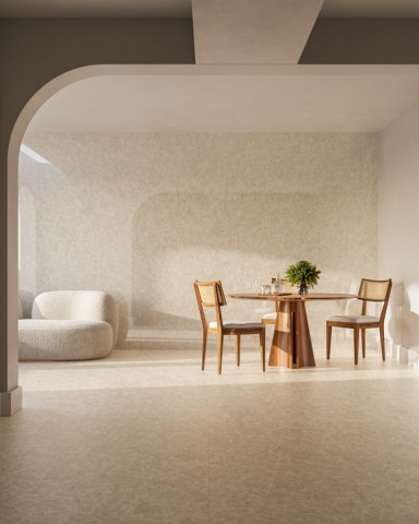 Sala de jantar e estar integrada em conceito aberto, com piso e parede em tom bege terroso suave e textura sutil de cimento queimado. No centro, uma mesa de jantar redonda de madeira com cadeiras de madeira e palhinha no encosto. À esquerda, emoldurado por um arco arquitetônico, avista-se um sofá curvo estofado em tecido claro. A iluminação natural suave projeta sombras no ambiente. Sala de jantar e estar integrada em conceito aberto, com piso e parede em tom bege terroso suave e textura sutil de cimento queimado. No centro, uma mesa de jantar redonda de madeira com cadeiras de madeira e palhinha no encosto. À esquerda, emoldurado por um arco arquitetônico, avista-se um sofá curvo estofado em tecido claro. A iluminação natural suave projeta sombras no ambiente.