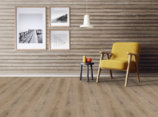 Sala de estar decorada com piso vinílico amadeirado em tom marrom claro. Ao fundo, uma parede revestida com réguas de madeira horizontais abriga três quadros com moldura clara e fotos em preto e branco. Uma poltrona amarela com pés de madeira se destaca ao lado de uma pequena mesa de centro preta e uma luminária pendente branca. Sala de estar decorada com piso vinílico amadeirado em tom marrom claro. Ao fundo, uma parede revestida com réguas de madeira horizontais abriga três quadros com moldura clara e fotos em preto e branco. Uma poltrona amarela com pés de madeira se destaca ao lado de uma pequena mesa de centro preta e uma luminária pendente branca.